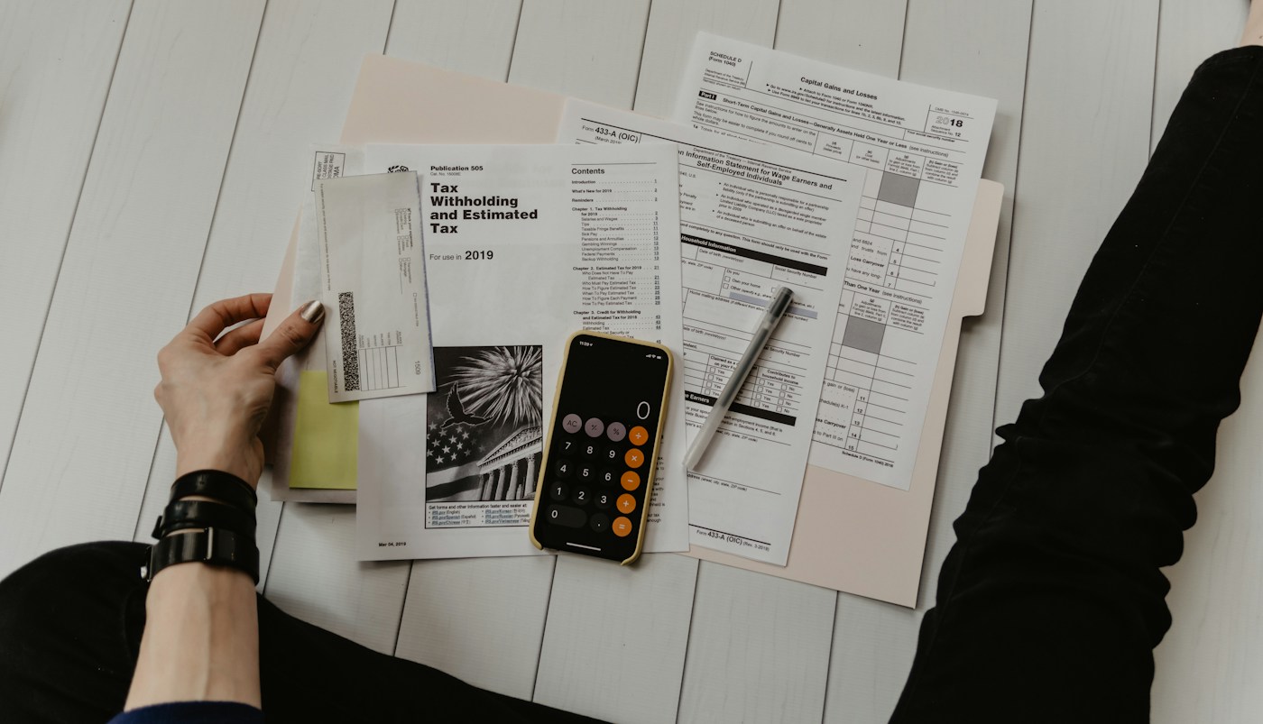 A person reviewing US tax paperwork with a calculator